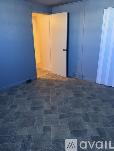 A room with a floor of stone tiles and a wall painted in blue.