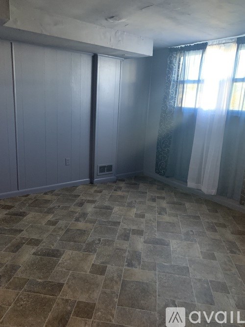 A room with a tiled floor and a window with curtains.