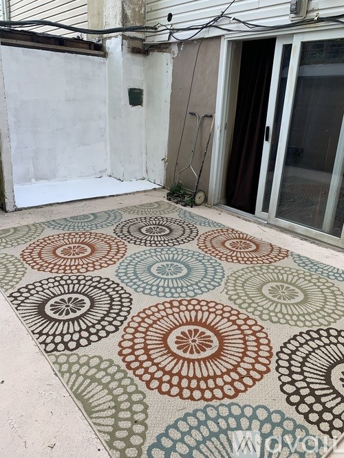 A patio with a circular patterned rug.