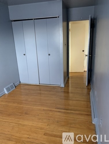 A room with wooden flooring and a window with a curtain.