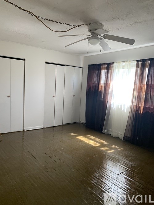 A room with a ceiling fan and wooden floors.