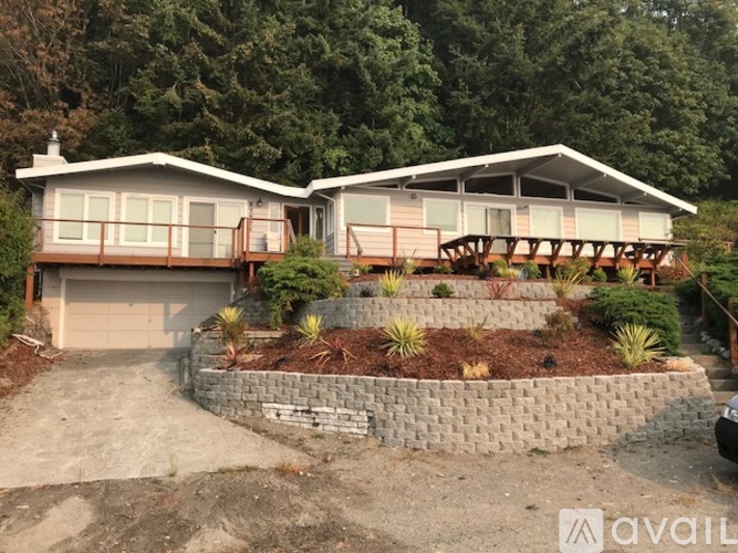 A house with a stone wall and a wooden deck.