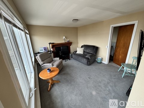 A living room with a grey carpet and a wooden coffee table.