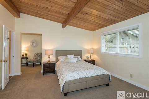 A bedroom with a large bed and a wooden ceiling.
