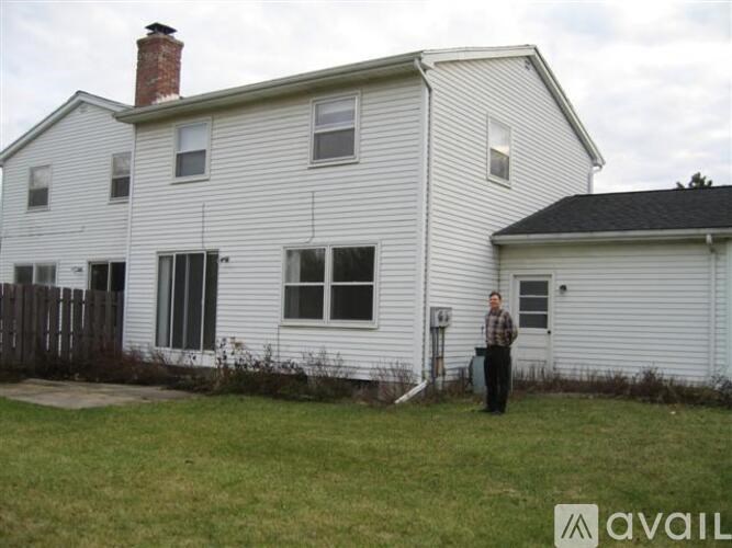 A man stands in front of a white house.