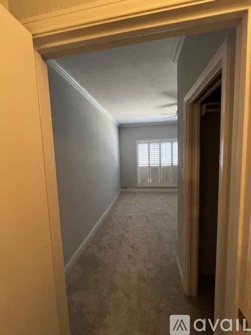 A hallway with a carpeted floor and a door on the right.