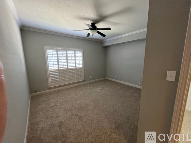 A room with a ceiling fan and a window with blinds.