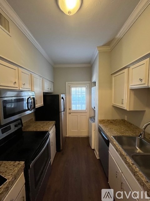 A kitchen with black appliances and wooden floors.