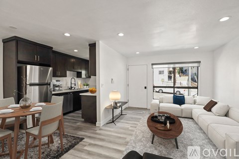 A modern kitchen with a dining table and a living room area.