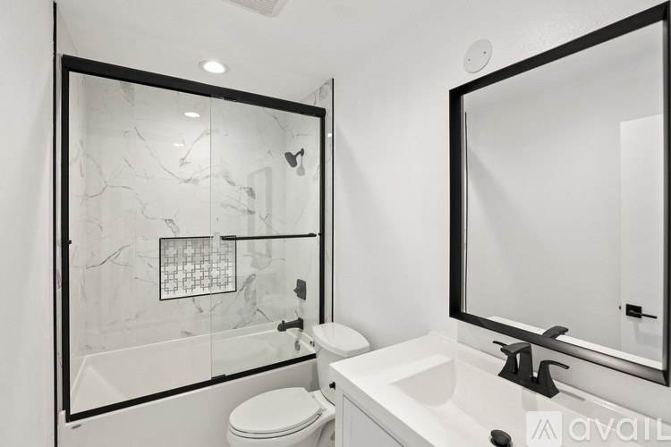 A bathroom with a marble patterned shower and a toilet.
