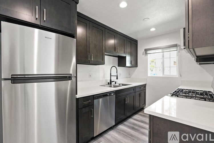 A kitchen with a stainless steel refrigerator and black cabinets.