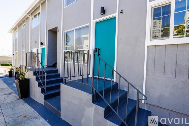 A modern house with a blue door and stairs leading to it.