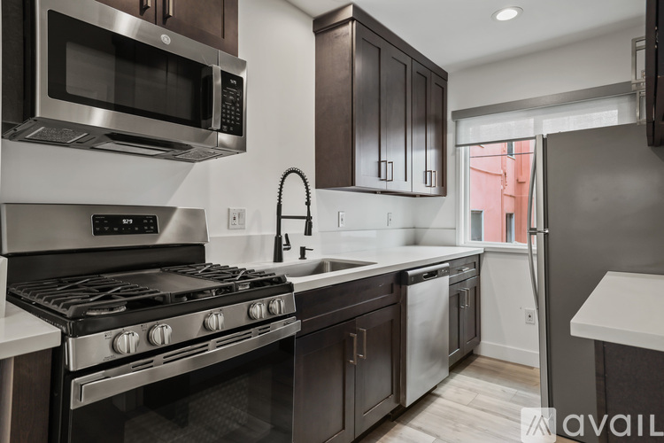 A modern kitchen with dark brown cabinets and stainless steel appliances.