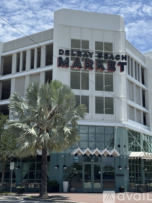 A white building with a Delray Beach Market sign on it.