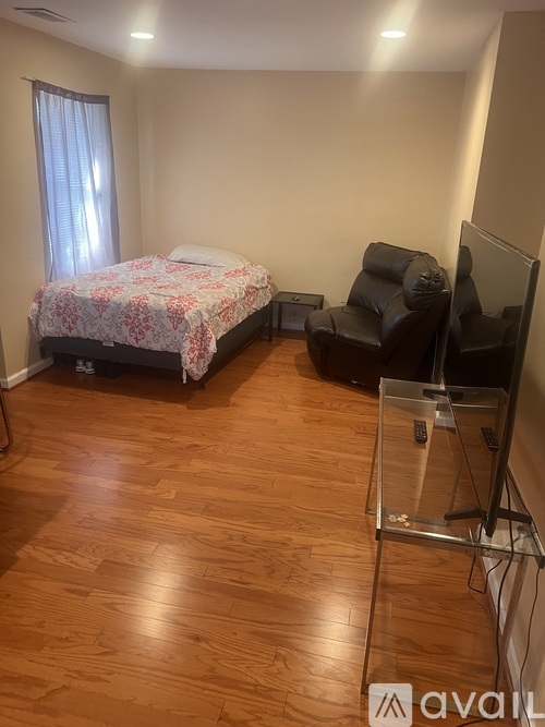 A bedroom with a bed, chair, and television.