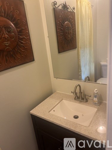 A bathroom with a sink and two sun artworks on the wall.