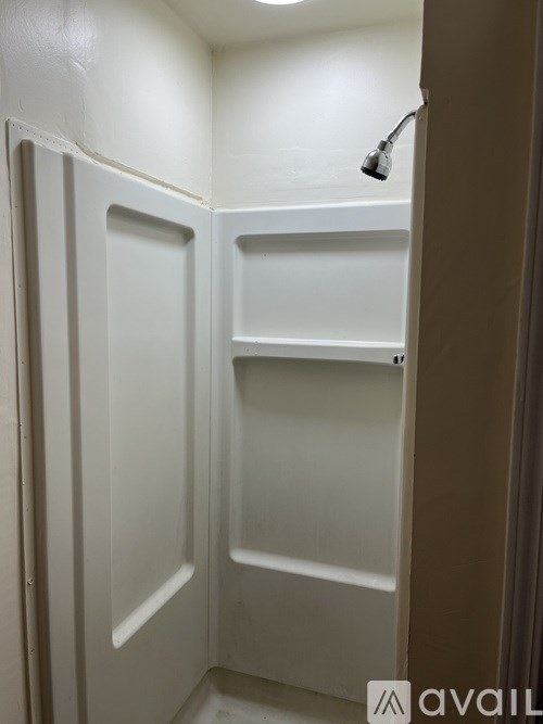 A small white closet with a light on.