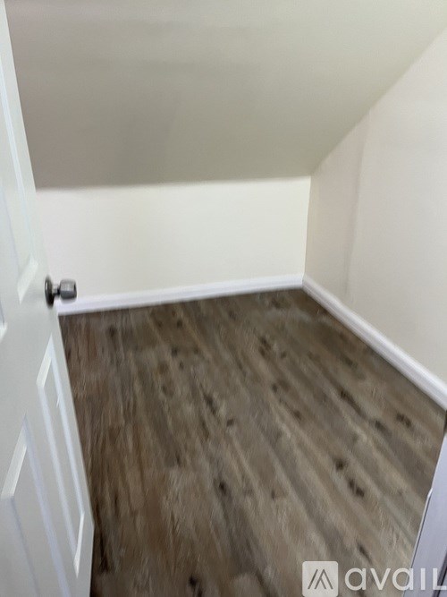 A room with a white door and wooden flooring.