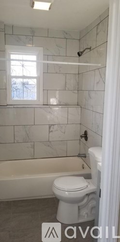 A white toilet sits in a bathroom with marble tile walls.