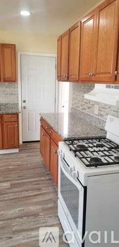 A kitchen with wooden cabinets and a white stove top oven.