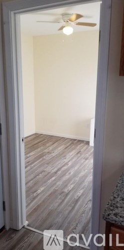 A room with a ceiling fan and wooden flooring.