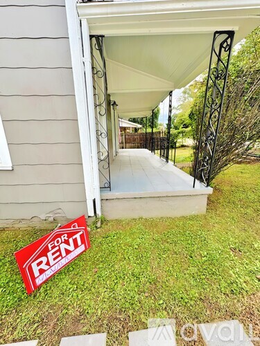 A red and white for rent sign is placed in front of a house.