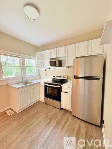 A kitchen with white cabinets and a stainless steel refrigerator.