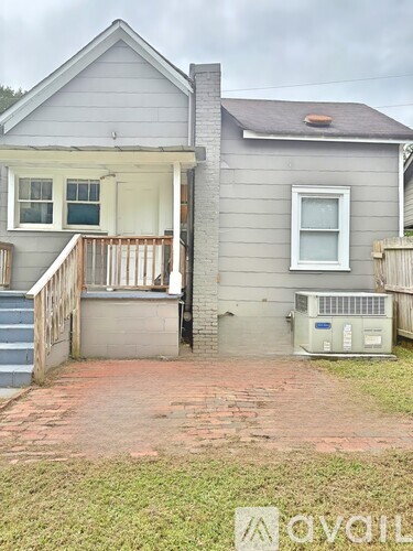 A grey house with a red brick walkway in front.
