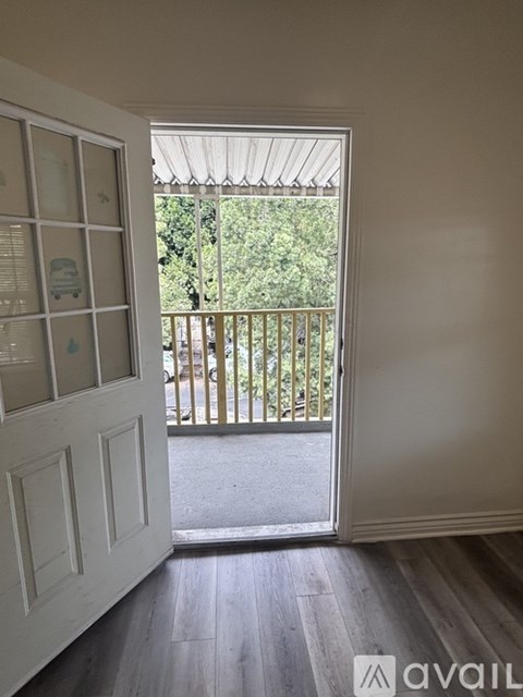 A room with a white door and a balcony with a railing.