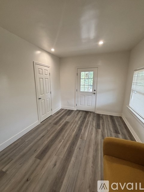 A room with a yellow chair and wooden flooring.