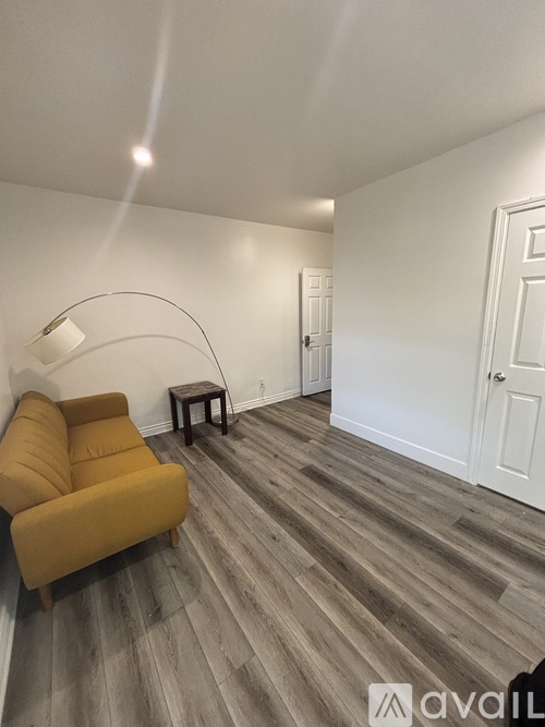 A living room with a yellow couch and a wooden floor.