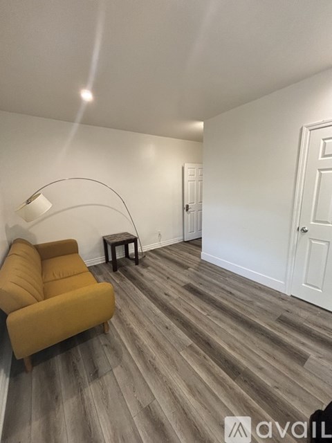 A living room with a yellow couch and a wooden floor.