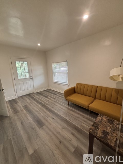 A living room with a yellow couch and wooden flooring.