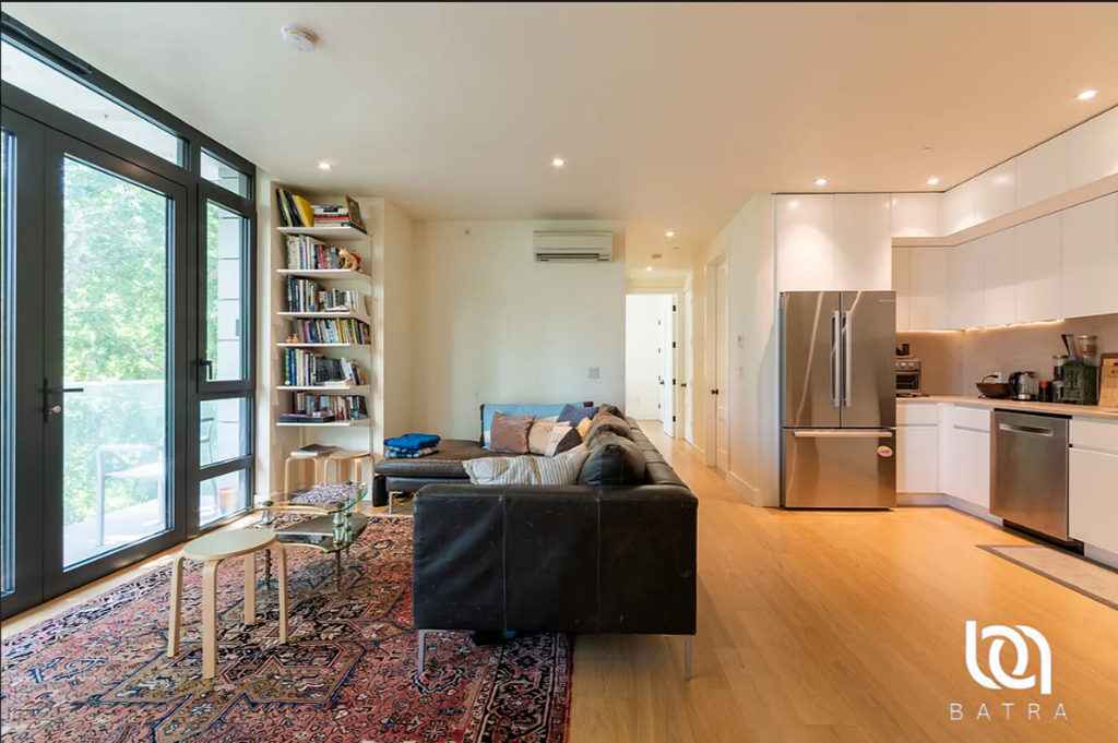 A modern living room with a black sofa and a wooden floor.
