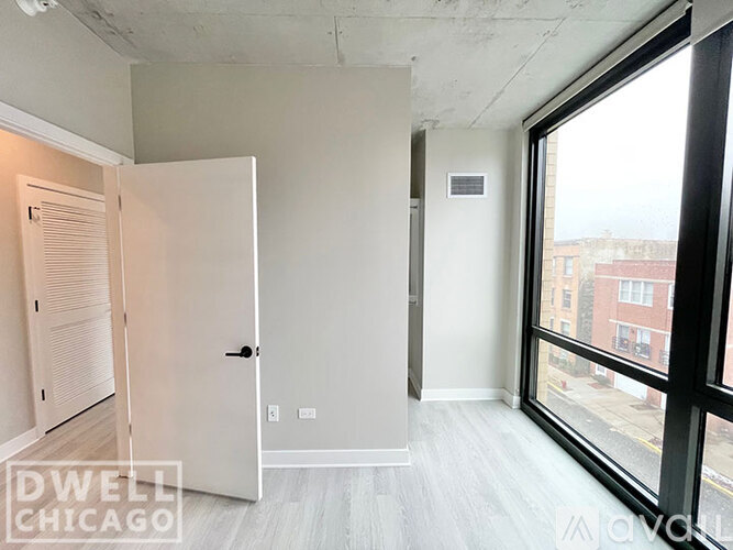 A white door is open to a room with a window.