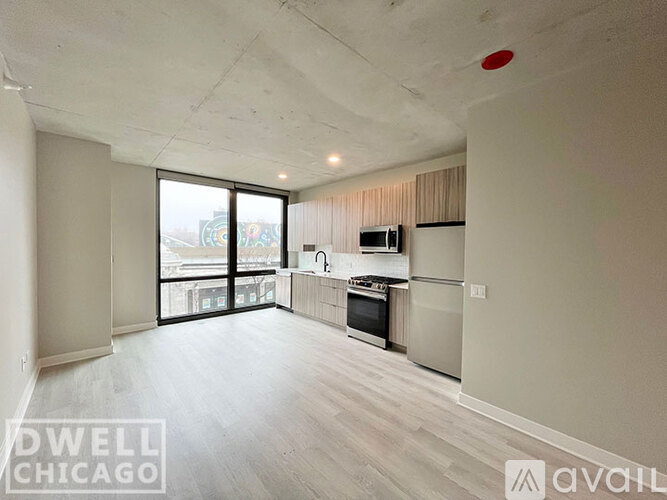 A spacious living room with a kitchen area in the background.