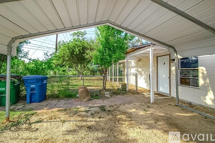 A patio area with a white roof and a tree in the background.