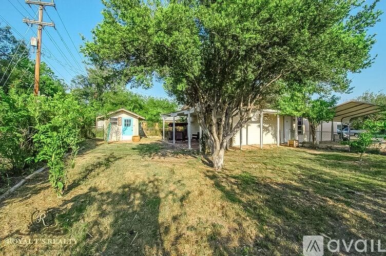 A tree in a yard with a house in the background.