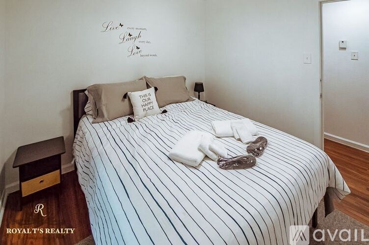 A bedroom with a bed, pillows, a nightstand, and a wall decal that says "Love is patient, love is kind".