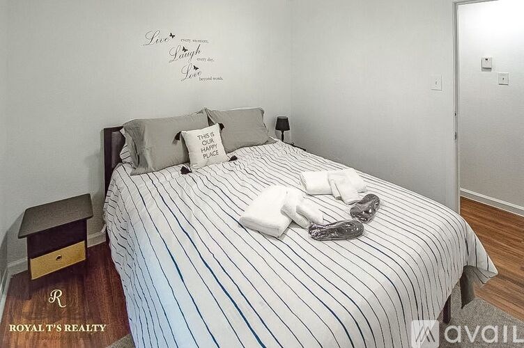 A bedroom with a bed, nightstand, and a wall decal that says "Love is patient, Love is kind".