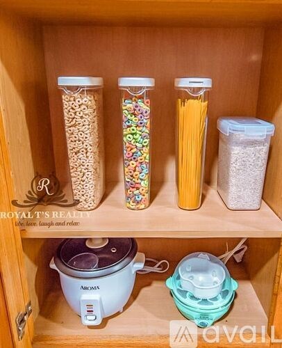 A kitchen cabinet with a rice cooker and containers of pasta, cereal, and flour.