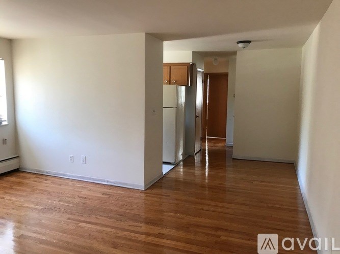 A room with wooden floors and white walls, with a door on the right side.