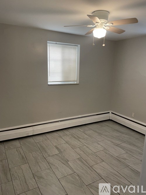 A room with a ceiling fan and a window with blinds.