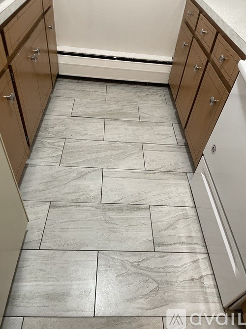 A kitchen with a tile floor and wooden cabinets.