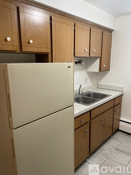A kitchen with a white fridge and brown cabinets.