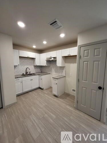 A kitchen with white cabinets and a grey door.