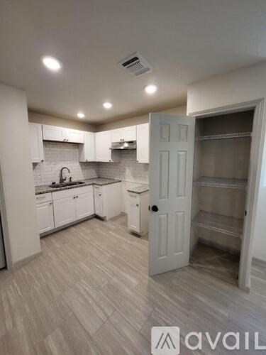 A kitchen with white cabinets and a white door leading to a pantry.