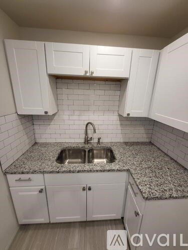 A kitchen with white cabinets and a granite countertop.