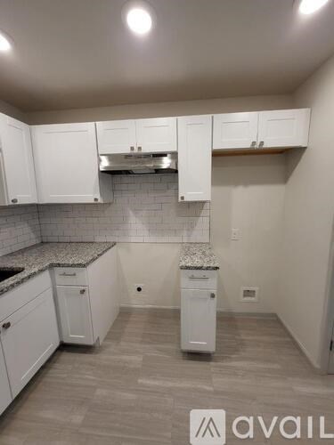 A kitchen with white cabinets and a granite countertop.