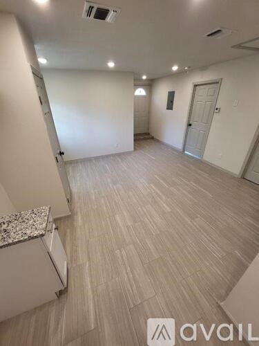A spacious room with a marble countertop and light wooden flooring.